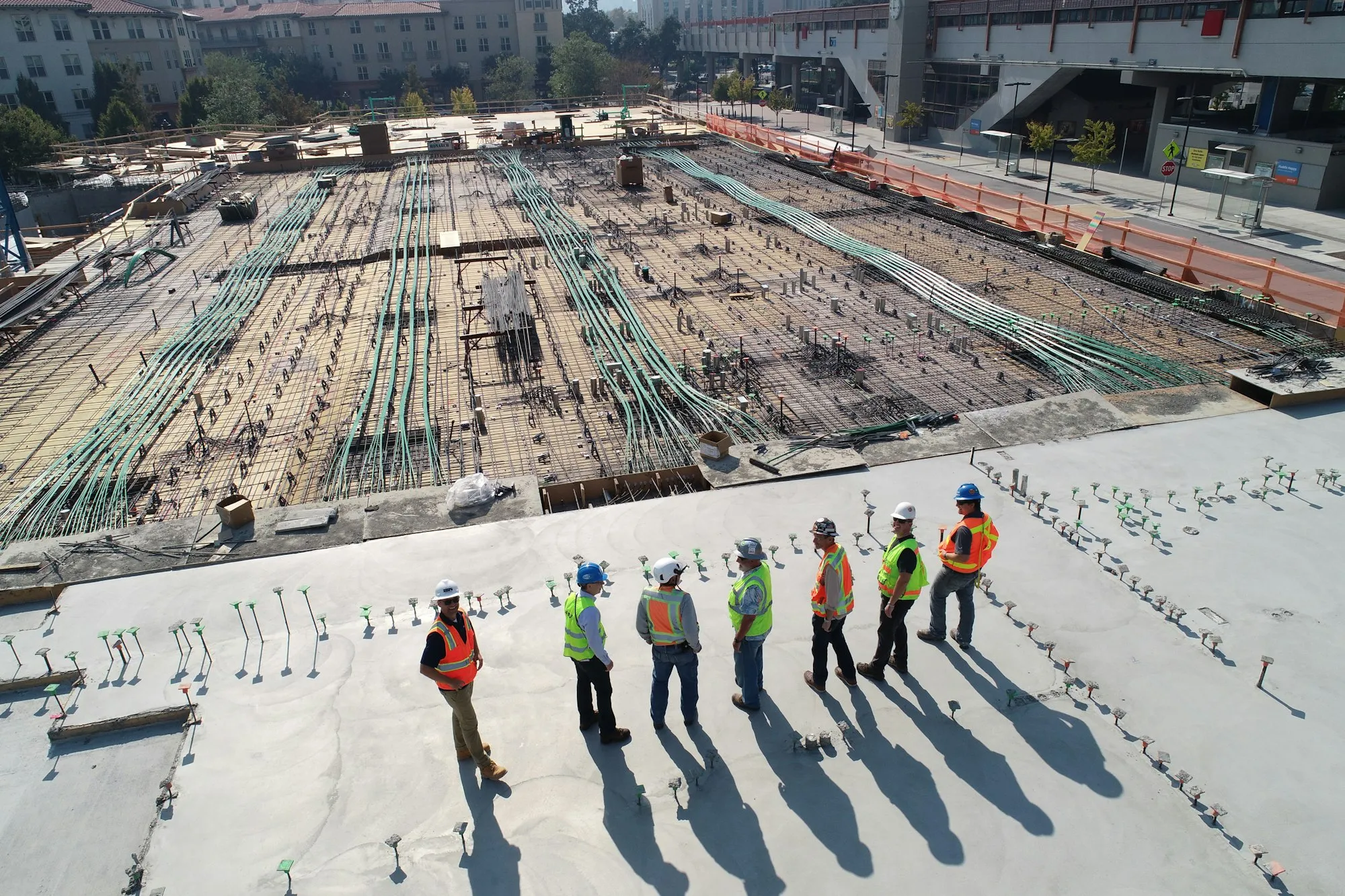 A crew of construction workers in safety vests and hard hats at an active job site, the kind of operation that runs on answered quote calls